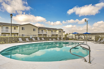 A swimming pool surrounded by chairs and apartment buildings.